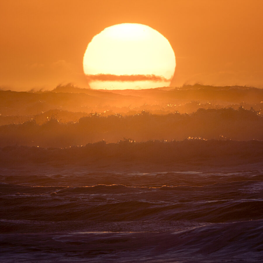 Sun setting behind waves New Zealand